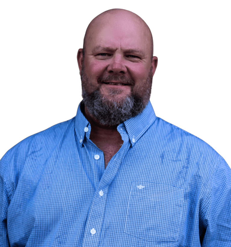 Raymond Black, a man with a beard wearing a blue checkered button-up shirt, standing and smiling against a plain white background.